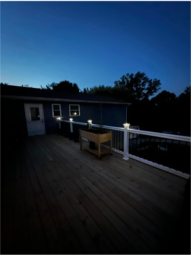 Two tone wooden deck with light brown floor and white banister with lights in post caps