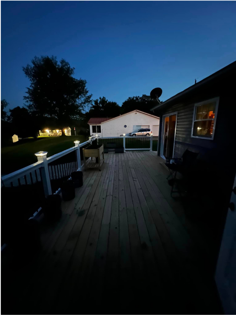 Two tone wooden deck with light brown floor and white banister with lights in post caps